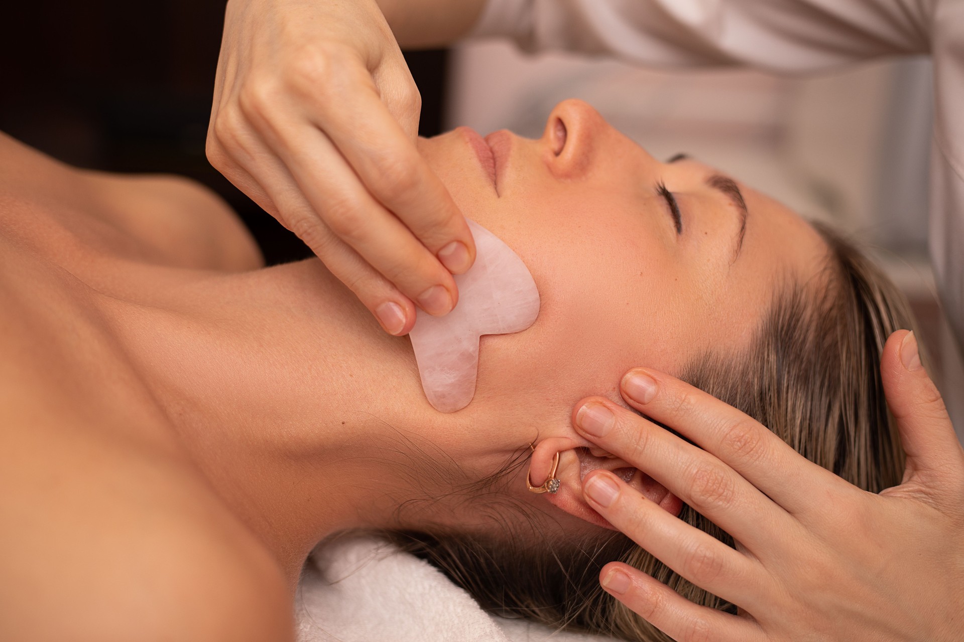 Jeune et belle femme pendant le massage traditionnel chinois - Gua Sha. Photo de plan rapproché. Traitement de beauté dans le salon SPA. Soins de la peau anti-âge